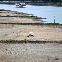 Ein Schiff fährt bei niedrigem Wasserstand auf dem Rhein an trocken gefallenen Buhnen vorbei