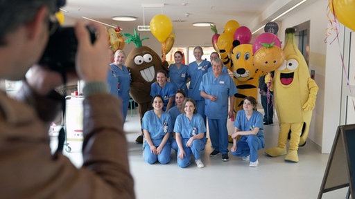 Krankenschwestern posieren mit zwei Frucht-Maskottchen