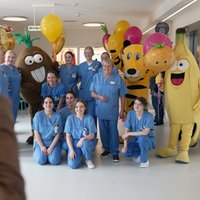 Krankenschwestern posieren mit zwei Frucht-Maskottchen