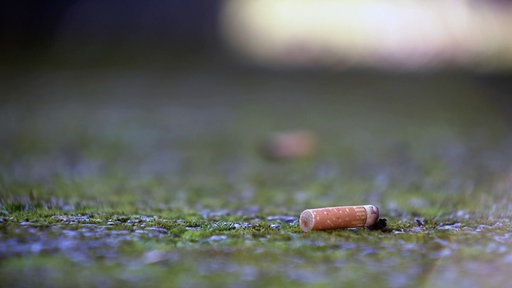Eine Kippe die auf einer Wiesenfläche liegt.