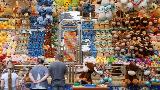 Eine Familie steht vor einem Libori-Stand mit Plüschtieren.
