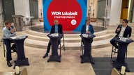 Vier Menschen sitzen auf Barhockern in einer Kirche und diskutieren.