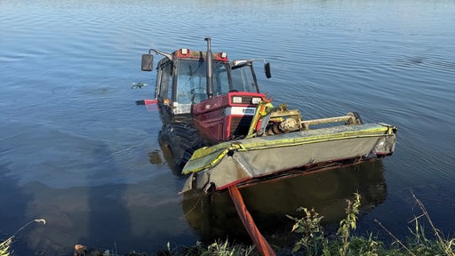 Ein Traktor liegt bis zur Hälfte in einem Fluss