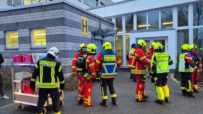 Feuerwehrmänner vor dem Eingang einer Schule. 