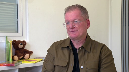 Markus Möhl, der Vorsitzende des Lunch Club e.V., sitzt in einem Raum und schaut in die Kamera.