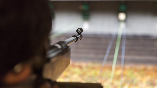 Jemand zielt mit einem Luftgewehr auf ein Ziel