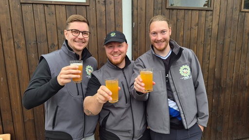 Drei Männer halten Gläser mit Apfelwein in der Hand