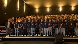 Die Spieler von Arminia Bielefeld stehen für ein Gruppenfoto im dunklen Kinosaal des Cinemaxx Bielefeld. 