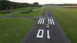 Ein Auto fährt über die Start- und Landebahn eines Flugplatzes