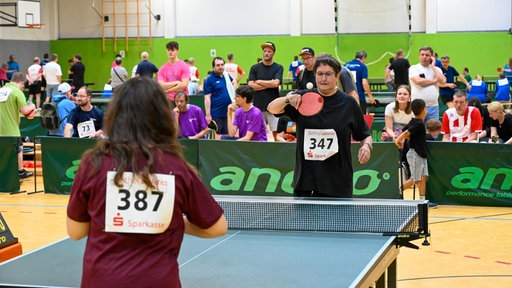 Zwei Frauen spielen Tischtennis, dahinter sind weitere Teams zu sehen.
