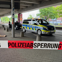 Ein Polizeiauto im Hintergrund. Im Vordergrund ein Absperrband mit der Aufschrift "Polizeisperrung".