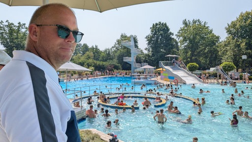 Schwimmmeister Björn Jann blickt durch seine Sonnenbrille auf das Schwimmbecken im Freibad Verl.