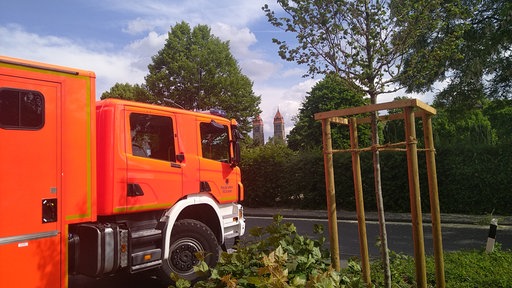 Ein Feuerwehrauto steht auf einer Straße, im Hintergrund sieht man eine Kirche
