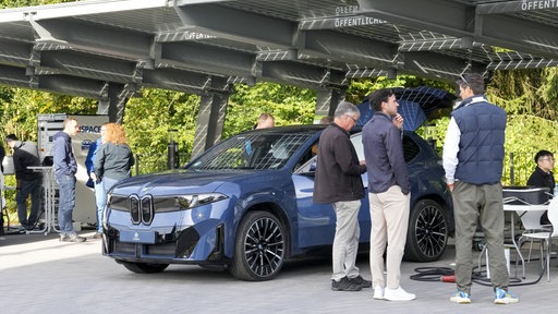 Ein Electro-BMW steht unter einem Dach mit PV-Elementen