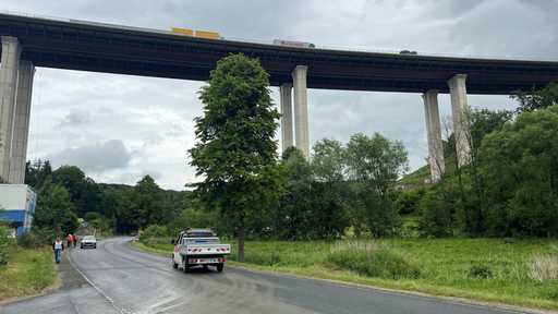 Eine Straße mit Fahrzeugen, darüber eine Talbrücke.