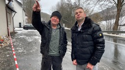 Ortsbürgermeister Dennis Beineke rechts vor beschädigtem Bürgerhaus 