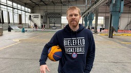 Ein Basketballspieler mit Ball in der Hand in einer Halle