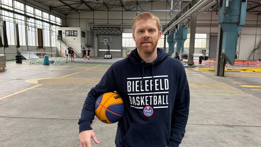 Ein Basketballspieler mit Ball in der Hand in einer Halle