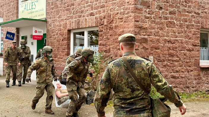 Bundeswehrsoldaten tragen bei einer Übung einen verletzten Menschen aus dem Haus.