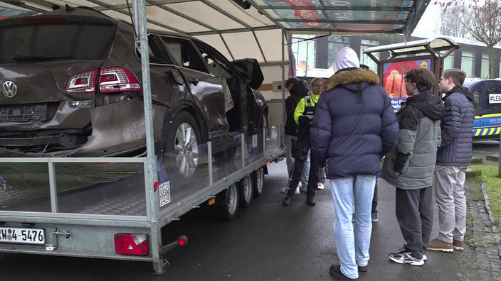 eine Polizistin neben einem verunfallten Auto