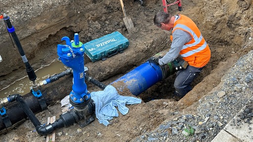 ein Bauarbeiter arbeitet an einer Wasserleitung in Graben der Baustelle