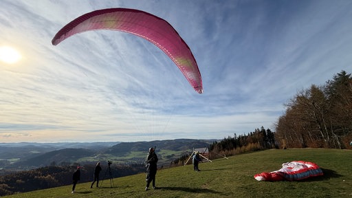 Ein Gleitschirmflieger mit offenen Schirm