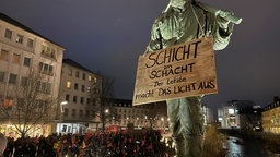 Bronzefigur eines historischen Arbeiters mit einem Schild um den Hals