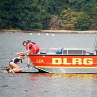 Ein Mädchen steigt auf ein DLRG Rettungsschiff auf dem Wasser.