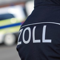 Ein Zollschriftzug auf Uniform vor einem Einsatzwagen.