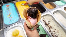 In der Auslage einer Eisdiele wird eine Eiswaffel gefüllt.