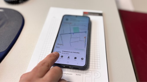 ein Handy mit Probealarm-Meldung