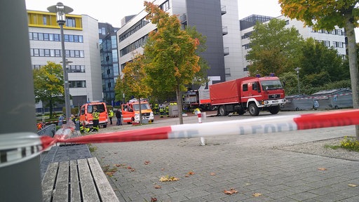 Einsatzfahrzeuge der Feuerwehr stehen hinter einem Absperrband.