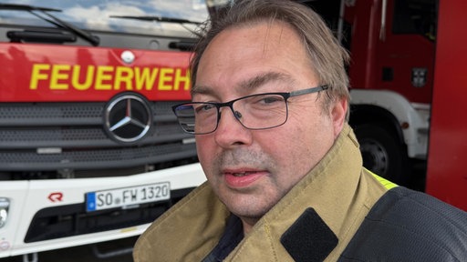 Karsten Korte steht vor einem Feuerwehrauto