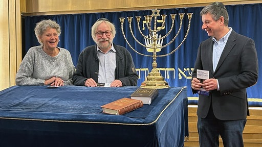 Drei Menschen mit jüdischen und christlichen Symbolen