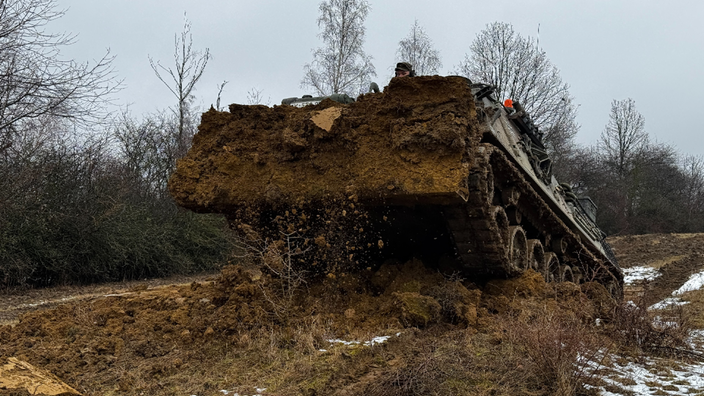 Ein Panzer der Bundeswehr gräbt den Feldboden um