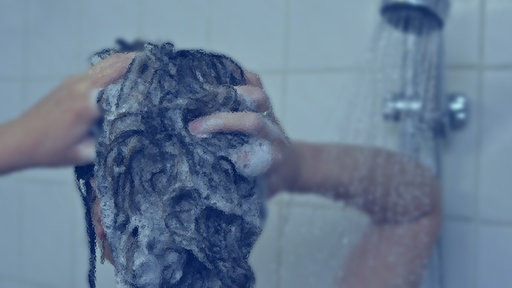 Eine Frau wäscht sich unter der Dusche die Haare