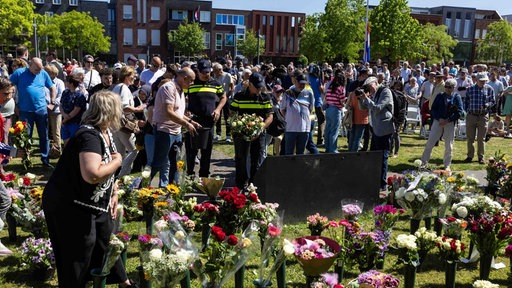 Viele Menschen legen Blumen an der Gedenkstätte nieder