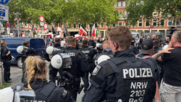 Eine Gruppe von Polizisten steht den Demoteilnehmenden gegenüber.