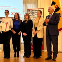 eine Gruppe von Schülerinnen und Schülern steht neben einer Lehrerin und dem Bundespräsidenten