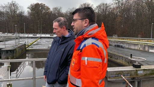 Klaus Rading, Mitarbeiter und André Kintrup, Leiter der technischen Betriebe Greven stehen zusammen auf dem Gelände der Kläranlage und unterhalten sich.