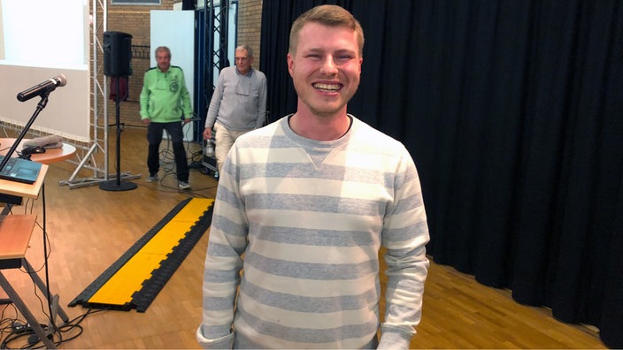 Ein junger Mann schaut lächelnd in die Kamera 