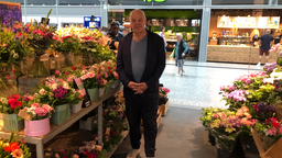 Ein Mann steht in einem Blumenladen zwischen Regalen