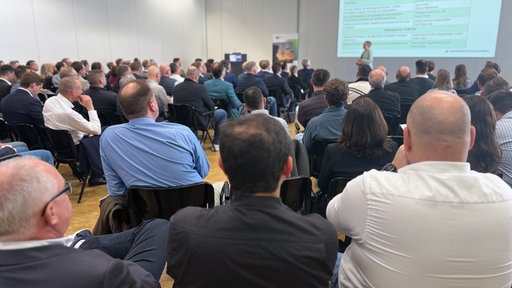 Veranstaltung „Road to Defence“ der SIHK in Hagen. Mehrere Menschen sitzen zusammen und hören sich einen Vortrag an.