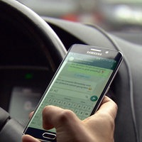 Person am Steuer benutzt Whatsapp auf dem Handy