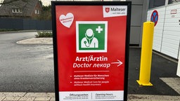 Es ist ein Aufsteller zu sehen, der auf das Angebot für Menschen ohne Krankenversicherung hinweist.