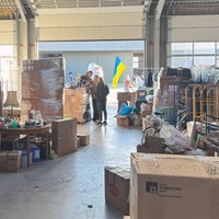 Drei Menschen stehen in einem Lager mit Spenden für die Ukraine