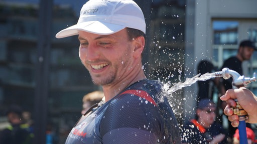 Triathlet wird mit Wasser abgekühlt