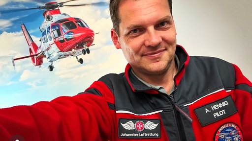 Bild von Rettungspilot, im Hintergrund ein Rettungshubschrauber