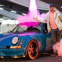 JP Kraemer vor einem blauen Sportwagen auf einer Bühne