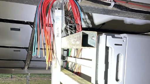 Beschädigte Kabel hängen an einer PV-Anlage herunter